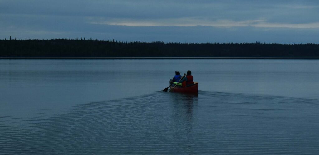 Youth in canoe on water at dusk